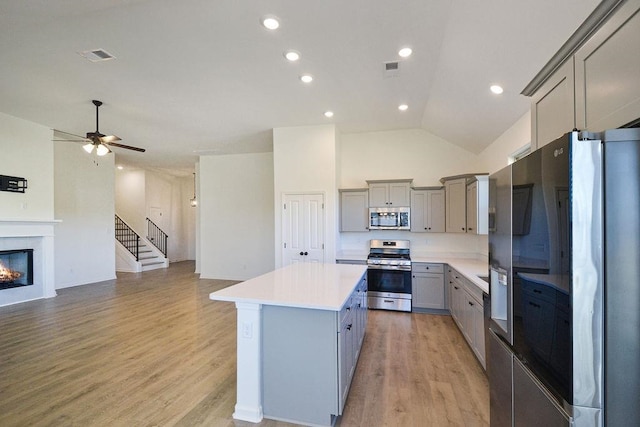 kitchen with gray cabinets, a center island, stainless steel appliances, and light wood-type flooring