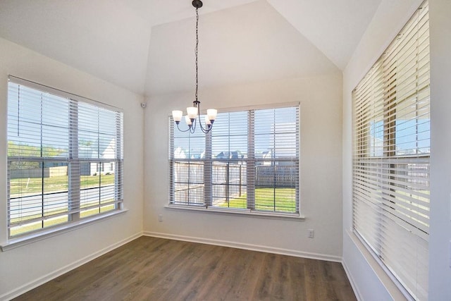 unfurnished dining area with a notable chandelier, dark wood-type flooring, vaulted ceiling, and a wealth of natural light