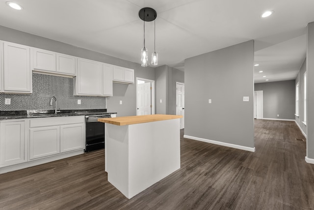 kitchen featuring white cabinets, wood counters, dark hardwood / wood-style floors, decorative light fixtures, and sink