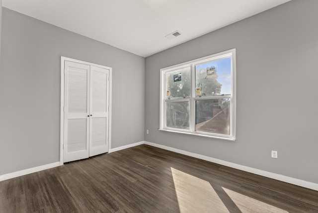 unfurnished bedroom featuring a closet and dark hardwood / wood-style flooring