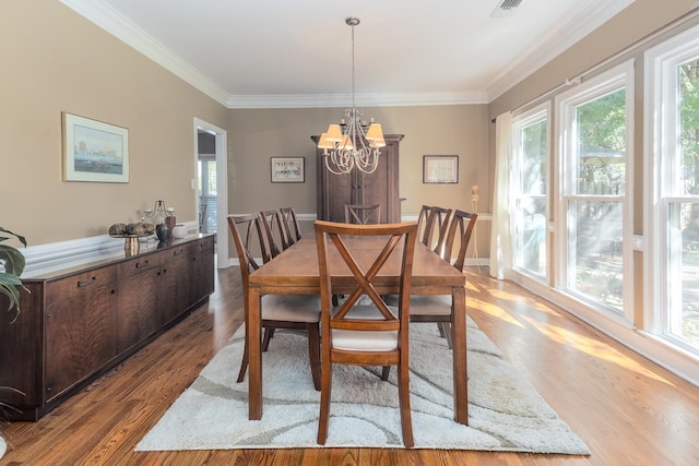 dining space featuring light hardwood / wood-style floors, ornamental molding, and a chandelier