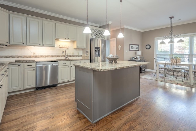 kitchen with white cabinets, hanging light fixtures, stainless steel appliances, and wood-type flooring