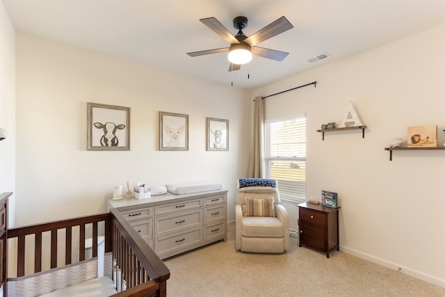 carpeted bedroom with a nursery area and ceiling fan