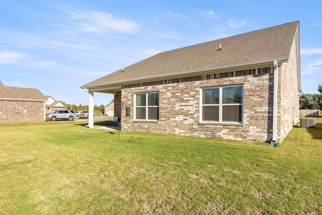 rear view of house featuring a lawn and central AC unit