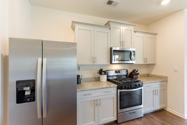 kitchen featuring appliances with stainless steel finishes, white cabinetry, and light stone countertops