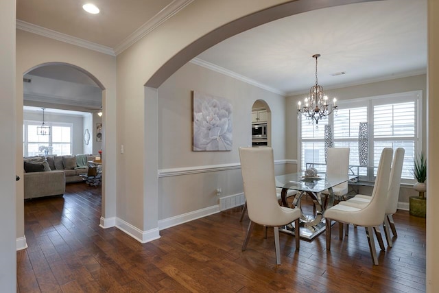 dining space featuring an inviting chandelier, ornamental molding, and dark wood-type flooring