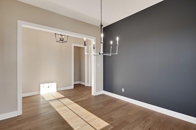 unfurnished dining area with hardwood / wood-style floors and an inviting chandelier