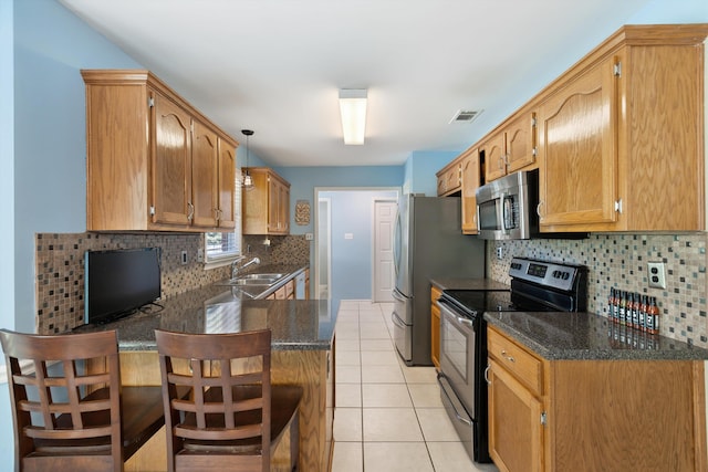 kitchen featuring hanging light fixtures, light tile patterned floors, appliances with stainless steel finishes, a breakfast bar area, and sink