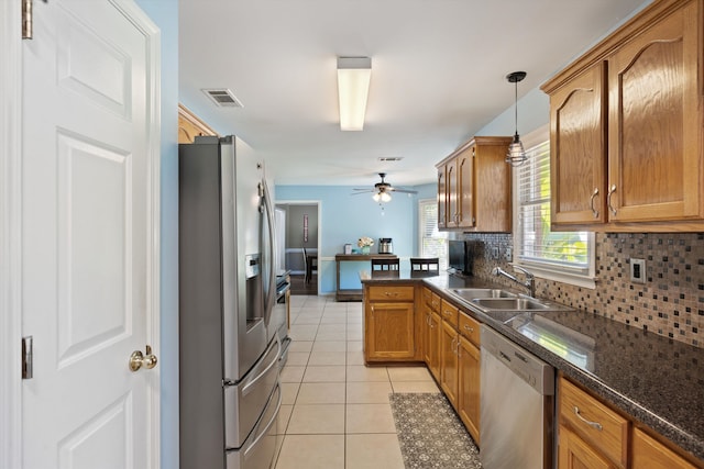 kitchen featuring kitchen peninsula, tasteful backsplash, hanging light fixtures, sink, and stainless steel appliances