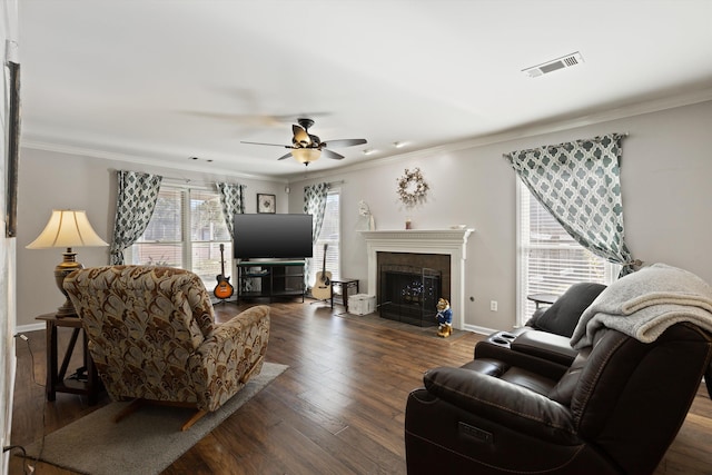 living room featuring ceiling fan, ornamental molding, dark hardwood / wood-style flooring, and a fireplace