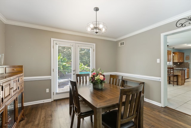 dining area with an inviting chandelier, ornamental molding, dark wood-type flooring, and french doors