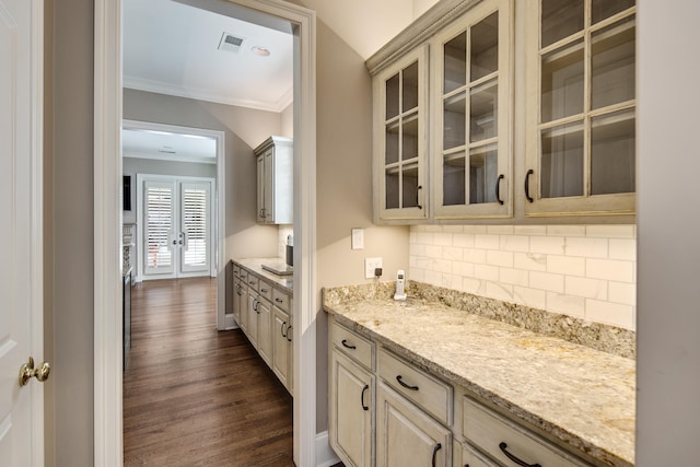 kitchen with ornamental molding, tasteful backsplash, light stone counters, and dark wood-type flooring