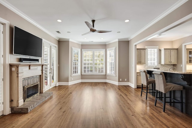 living room with ornamental molding, hardwood / wood-style floors, a fireplace, and a wealth of natural light