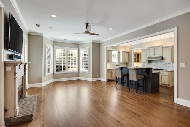 living room with dark wood-type flooring, a brick fireplace, crown molding, and ceiling fan