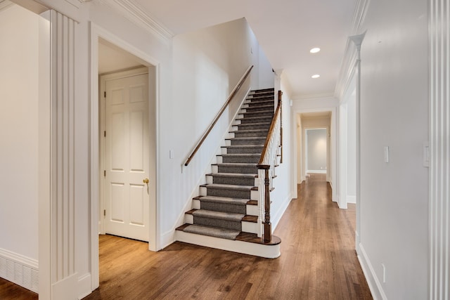 stairs with ornamental molding and hardwood / wood-style floors