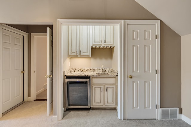 bar with lofted ceiling, cream cabinets, light colored carpet, and sink