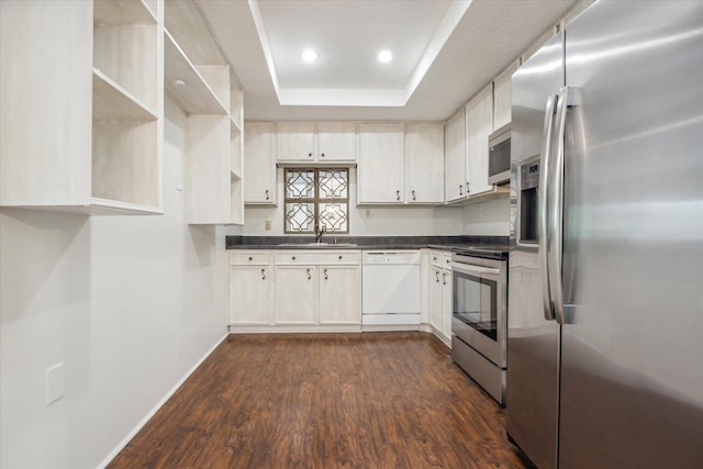 kitchen featuring appliances with stainless steel finishes, sink, a raised ceiling, dark hardwood / wood-style flooring, and white cabinets