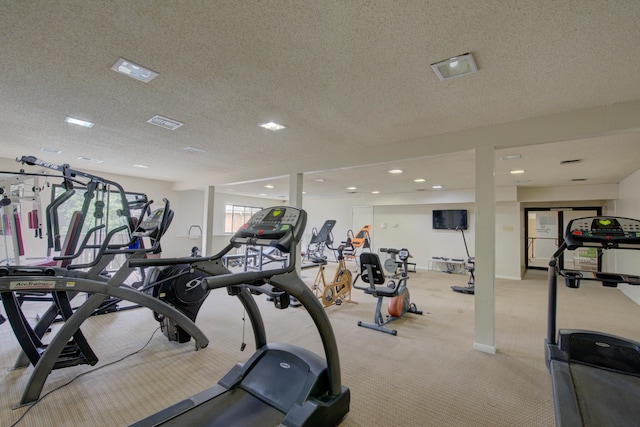 exercise room with a textured ceiling and light colored carpet