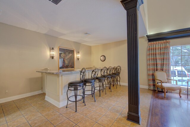 kitchen featuring ornate columns, a breakfast bar area, kitchen peninsula, and light hardwood / wood-style floors