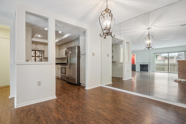 interior space featuring appliances with stainless steel finishes, a notable chandelier, decorative light fixtures, and dark hardwood / wood-style flooring