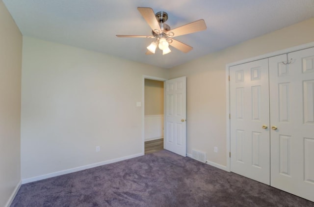 unfurnished bedroom with a closet, dark carpet, and ceiling fan