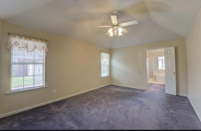 empty room featuring dark colored carpet and a wealth of natural light