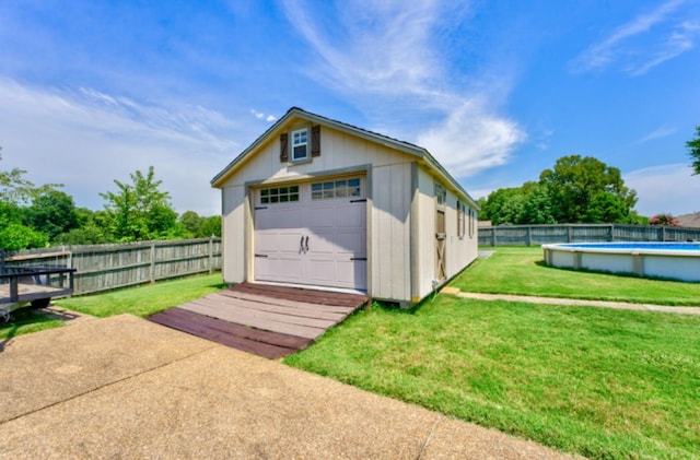 rear view of property featuring a yard, a fenced in pool, an outbuilding, and a garage