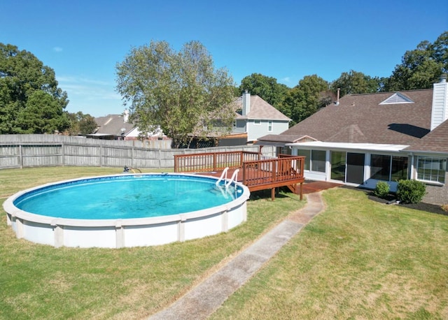 view of swimming pool with a yard, a sunroom, and a wooden deck