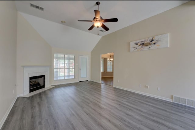 unfurnished living room with a tiled fireplace, hardwood / wood-style flooring, high vaulted ceiling, and ceiling fan