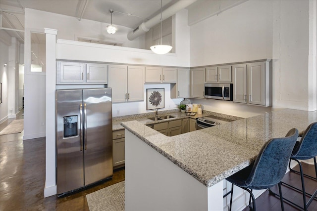 kitchen featuring pendant lighting, stainless steel appliances, a towering ceiling, and kitchen peninsula