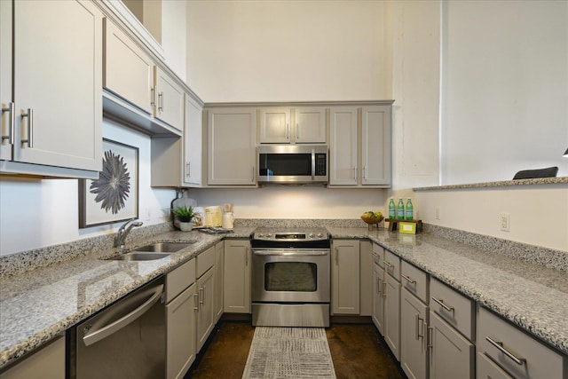 kitchen with stainless steel appliances, light stone countertops, and sink