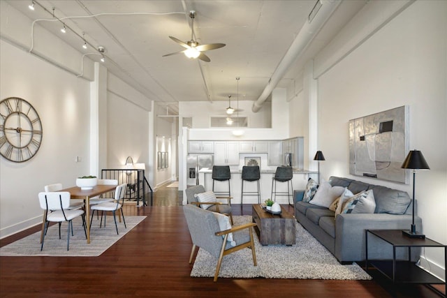 living room with ceiling fan, a towering ceiling, and dark hardwood / wood-style flooring