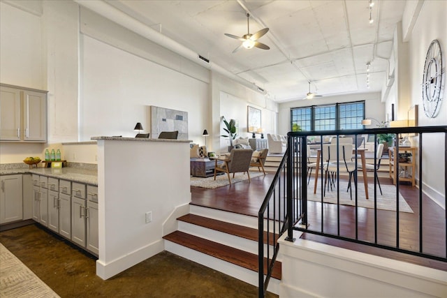 stairway with concrete floors, ceiling fan, and rail lighting