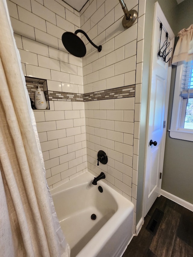 bathroom featuring wood-type flooring and shower / tub combo