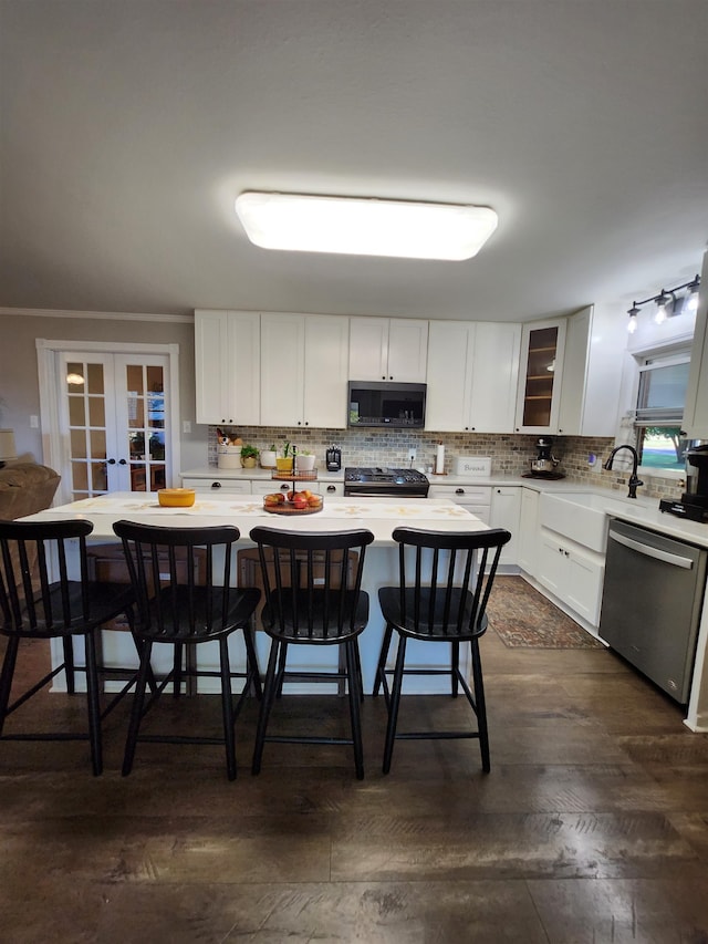 kitchen featuring dishwasher, a breakfast bar area, white cabinets, black gas stove, and french doors