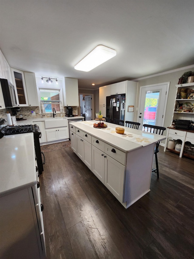 981 Durhamville Rd, Ripley, TN 38063 - kitchen featuring black fridge with ice dispenser, a kitchen island, dark wood-type flooring, white cabinets, and a sink