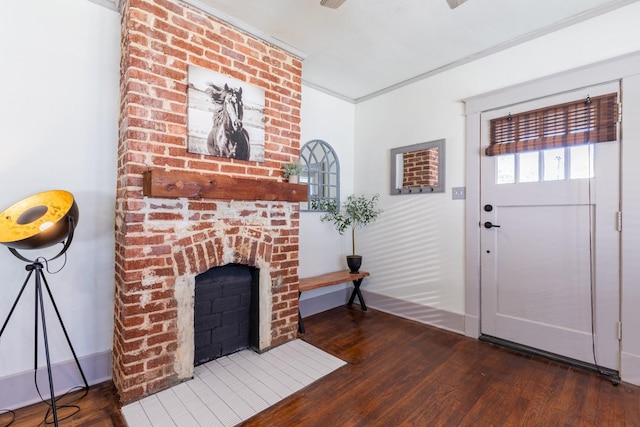 foyer entrance with dark wood-type flooring, crown molding, and a fireplace