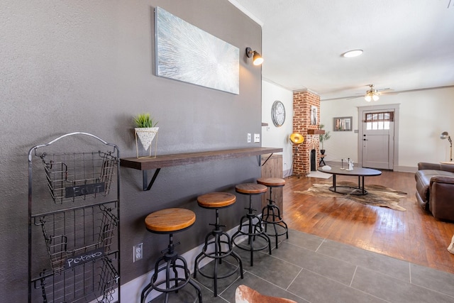 bar featuring ornamental molding, ceiling fan, and dark hardwood / wood-style flooring