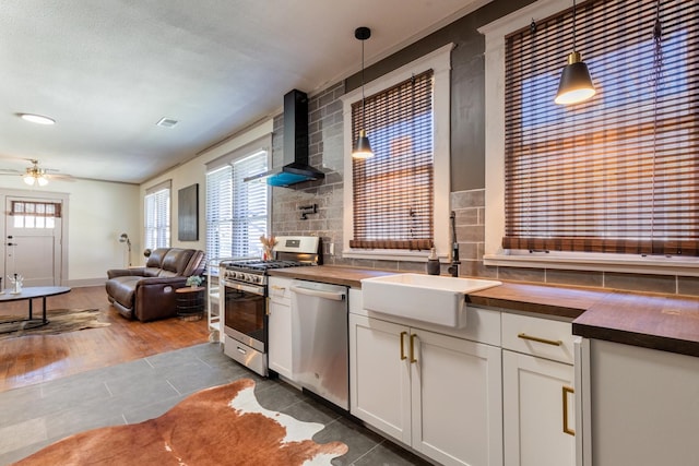 kitchen with wood counters, wall chimney range hood, and decorative light fixtures