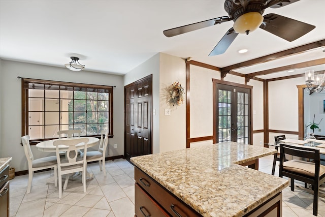 kitchen featuring a center island, ceiling fan with notable chandelier, light stone counters, and light tile patterned floors