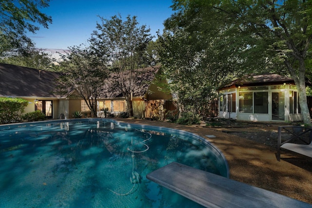 view of swimming pool featuring a diving board