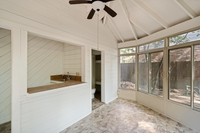 unfurnished sunroom featuring sink, vaulted ceiling with beams, and ceiling fan