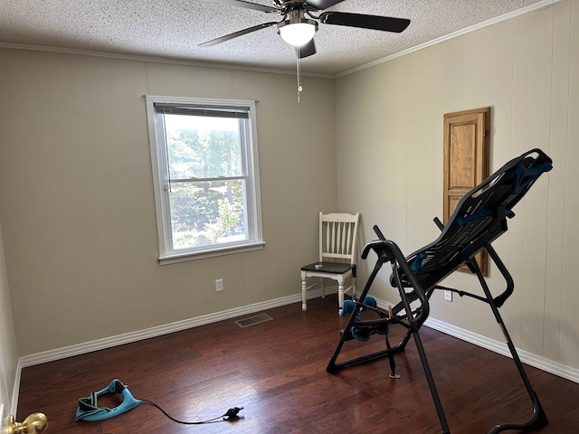 workout area with dark wood-type flooring, ceiling fan, ornamental molding, and wooden walls