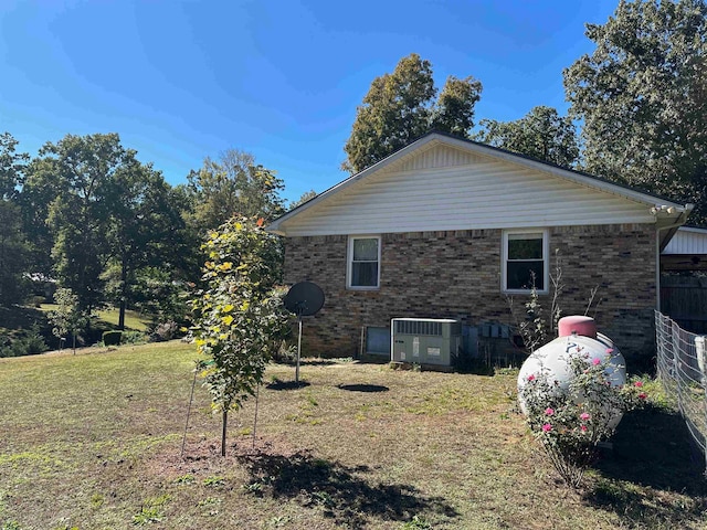 view of side of home with cooling unit and a lawn