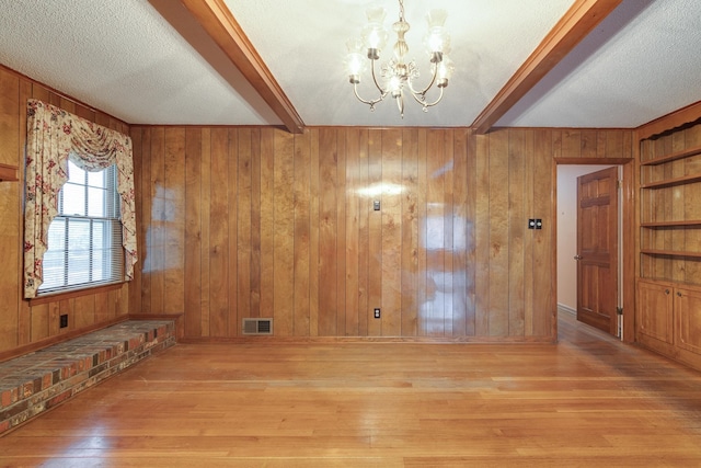 foyer entrance with light hardwood / wood-style flooring, wooden walls, and an inviting chandelier