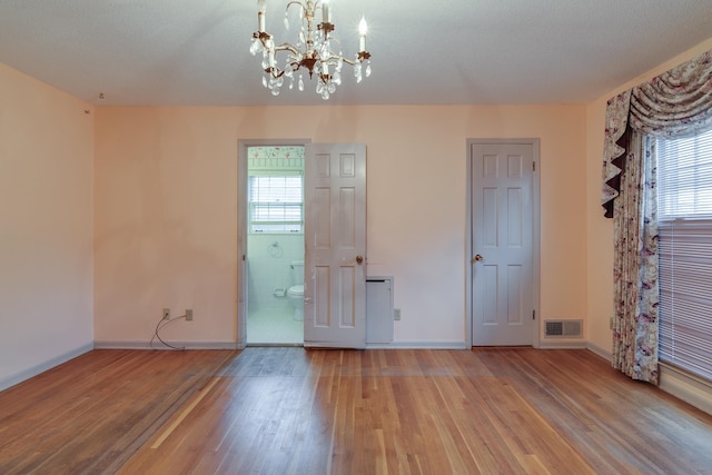 unfurnished room with a chandelier, plenty of natural light, hardwood / wood-style floors, and a textured ceiling