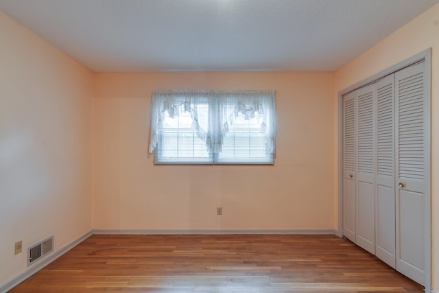 unfurnished bedroom with a closet and light hardwood / wood-style flooring