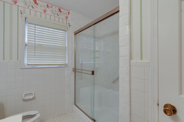 bathroom with tile patterned floors, toilet, tile walls, and a shower with shower door