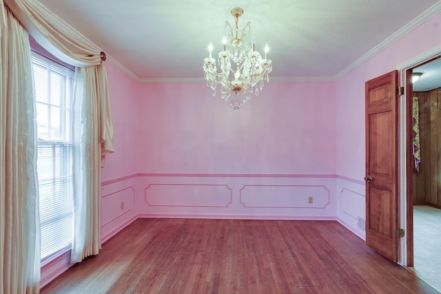 spare room with a notable chandelier, hardwood / wood-style flooring, and crown molding