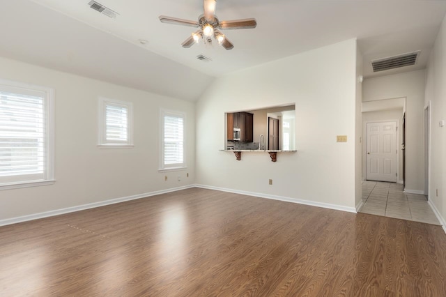 unfurnished living room with lofted ceiling, ceiling fan, sink, and dark hardwood / wood-style flooring